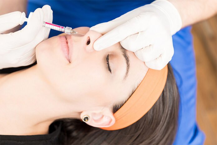 A cosmetic practitioner injects liquid into the nose of a patient to change its shape