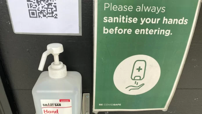 A close-up shot of hand sanitiser and a QR code outside a cafe in Hobart's CBD.